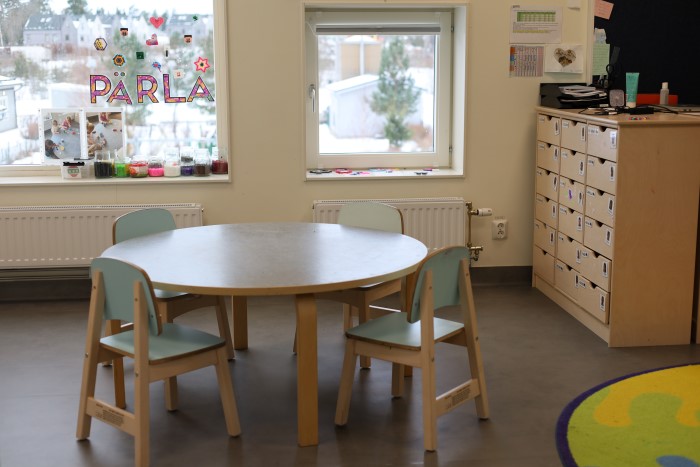 Bord inne på förskolan, framför ett fönster där det står "pärla".